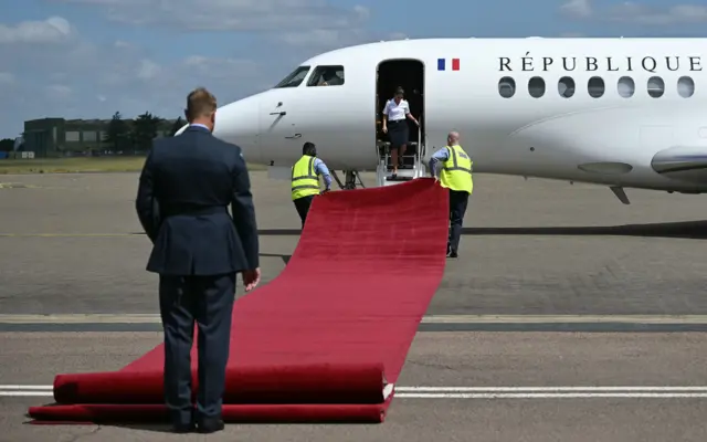 Ground staff roll out a red carpet for the disembarkation of the President of France Emmanuel Macron and his wife Brigitte Macron