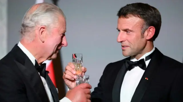 King Charles and Macron raise their glasses to one another while wearing smart clothing