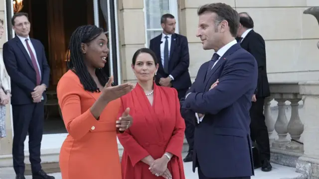 Kemi Badenoch, Priti Patel and Emmanuel Macron stand outside Lancaster House