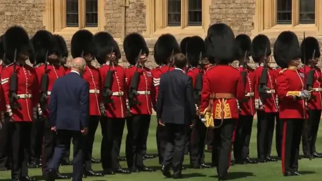 Charles and Macron walking in front of royal guard