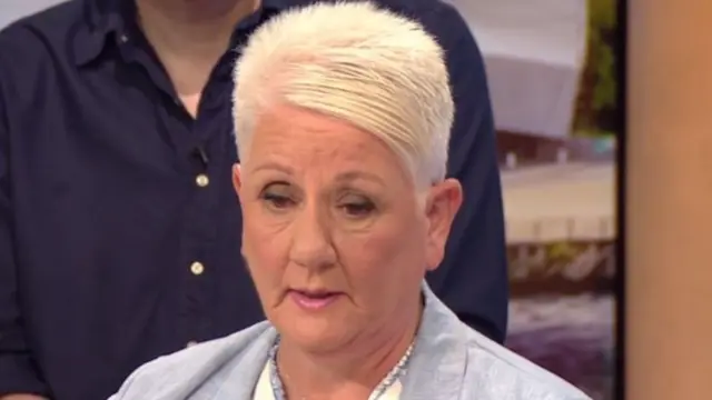 Middle aged woman with short-cropped platinum hair, baby blue blazer