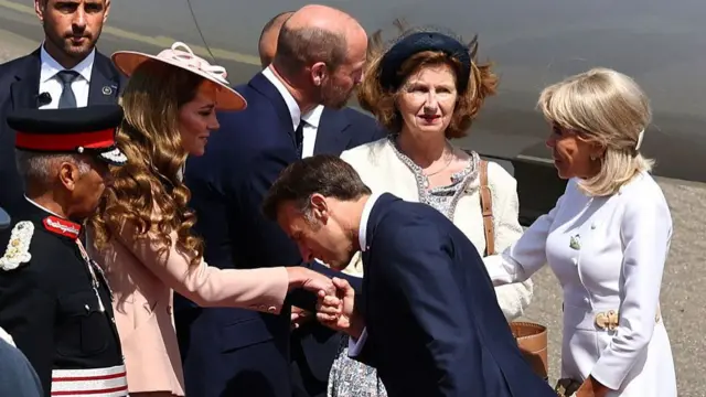 Princess of Wales and Prince of Wales greet Emmanuel Macron and his wife, Brigitte. Macron kisses Princess Catherine’s hand, while Prince William shakes Brigitte’s hand