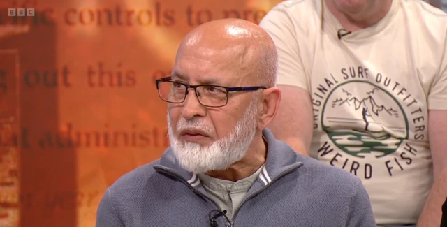 Mohammad Rasul has a short white beard and wears black, metal rimmed glasses