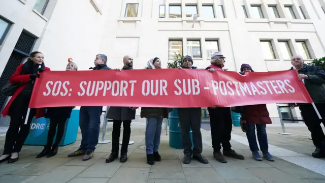 Protestors hold banner reading 'Support our sub-postmasters'