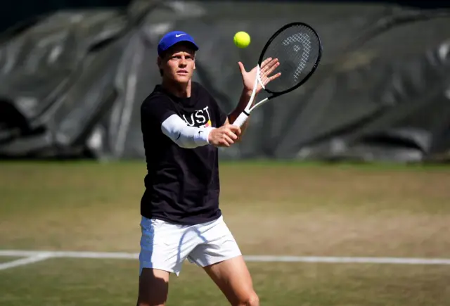 Jannik Sinner practising with his arm strapped
