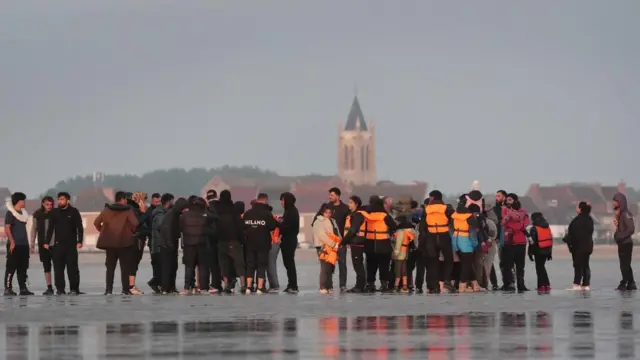 People thought to be migrants wait on the beach at Gravelines, France, to board a small boat in an attempt to reach the UK by crossing the English Channel