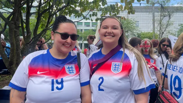 England fans Catherine and Charlotte, wearing England kit, smile at a fan event