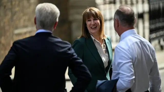 Reeves smiling and talking to two men