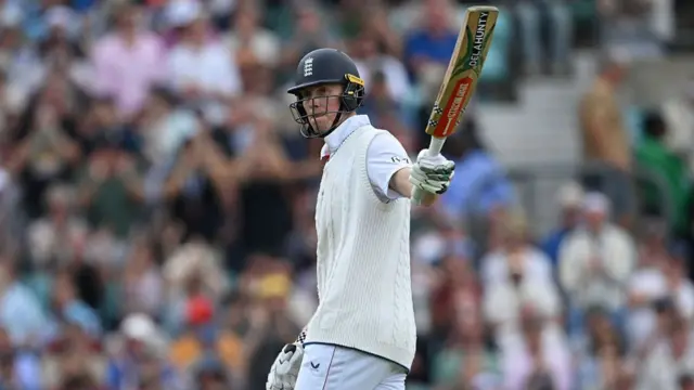 Zak Crawley lifts his bat to thank the crowd after reaching his half century vs India.