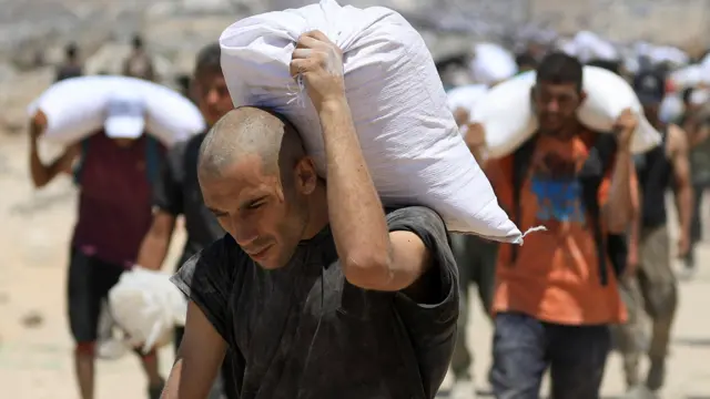 Palestinians carry aid supplies that entered Gaza through Israel