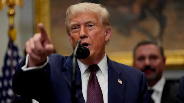 donald trump points towards the camera in the oval office