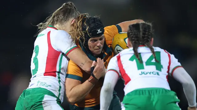Australia player is tackled by two Wales players