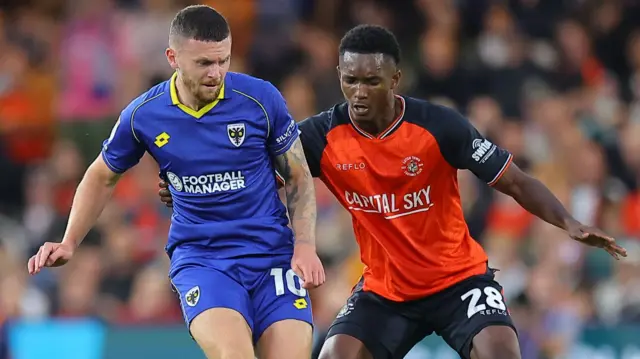 Josh Kelly of AFC Wimbledon and Christ Makosso of Luton Town