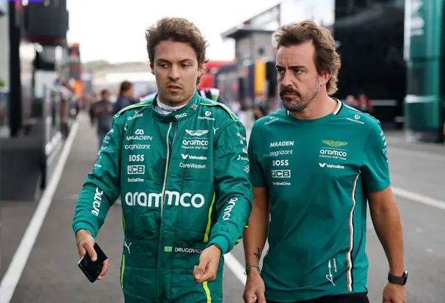 Felipe Drugovich walks in the paddock with Fernando Alonso