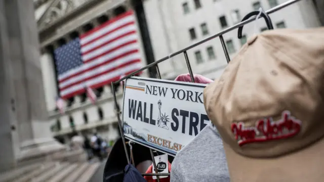A Wall Street sign in front of a large American flag in New York