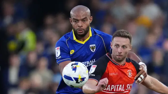 Luton Town's Jordan Clark (right) and AFC Wimbledon's Ryan Johnson battle for the ball