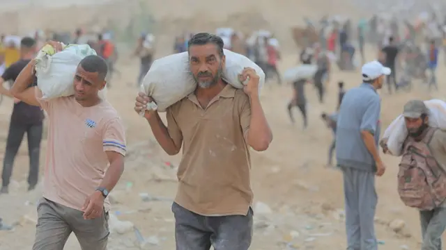 Men carry sacks of flour on their shoulders