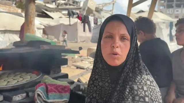 Fatma sits in front of an open fire where she bakes bread