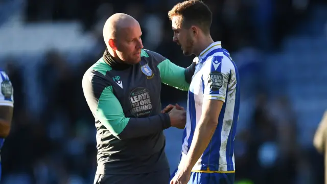 Henrik Pedersen, left, consoles Sheffield Wednesday player Will Vaulks, right, with one hand on his shoulder and the other shaking hands with the player