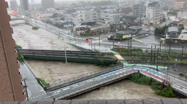 Screengrab of video footage shows a local river’s water level dangerously approaching ground level due to heavy rainfall in Japan.