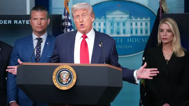 Donald Trump stands with arms spread at podium