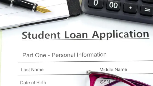 A student loan application, with money next to it in amounts, and glasses resting on the application