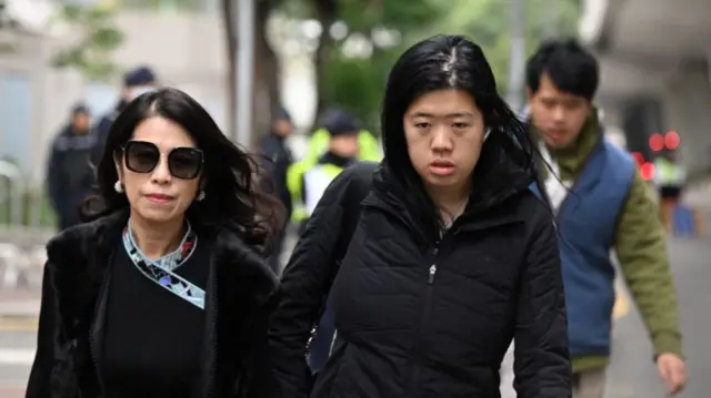 Front view of Teresa Lai and Claire Lai, Jimmy Lai's wife and daughter, walking on a street, wearing black jackets