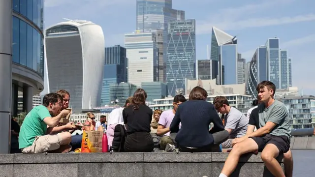 People have lunch with a sunny view of the City of London's financial district in the background
