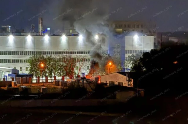A photo, taken at night, showing plumes of smoke rising from a building