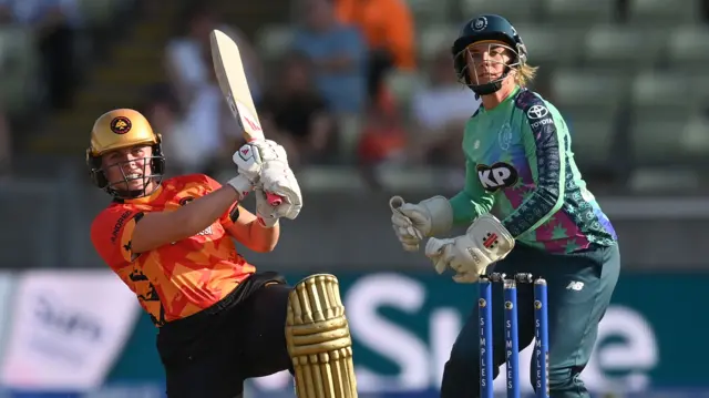 Ailsa Lister hits out watched by Lauren Winfield-Hill during the The Hundred match between Birmingham Phoenix and Oval Invincibles