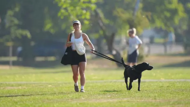 A woman walking her dog on Tooting Bec Common in London