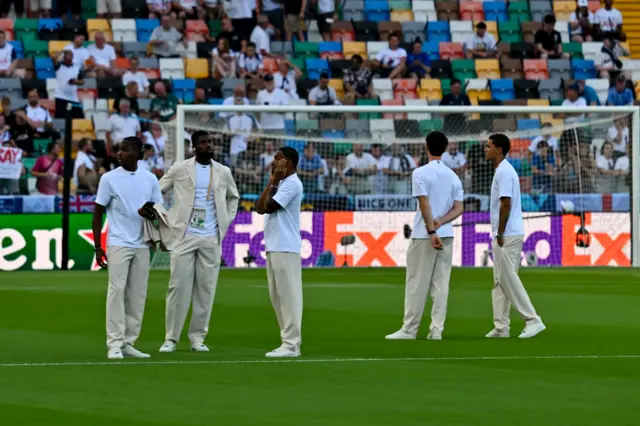 Tottenham players stand in white suits before the game