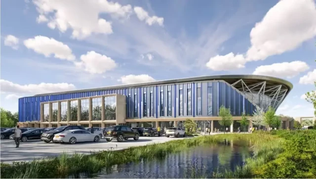 A CGI image of Oxford United's potential new stadium, with cars parked outside it and a pond in front of it.
