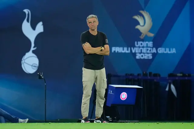 Enrique stands with arms folded and a glum expression on the touchline