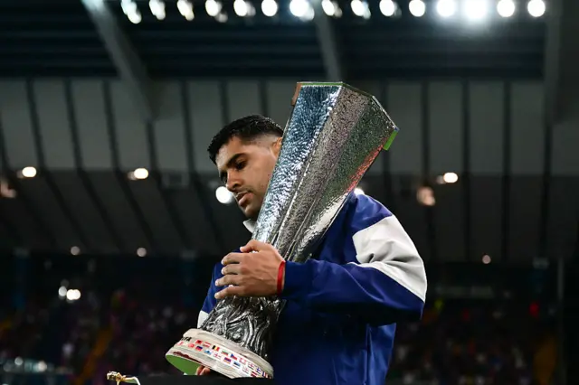 Cristian Romero walks out with the Europa League trophy.