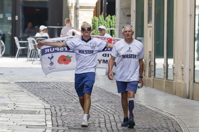 Spurs fans walk in shirts with an England flag
