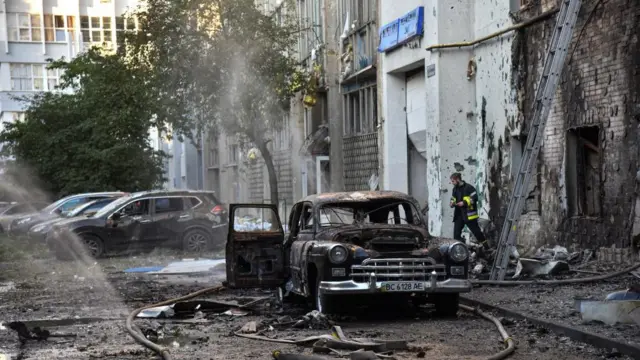 A firefighter works at the site of buildings and cars damage in Lviv