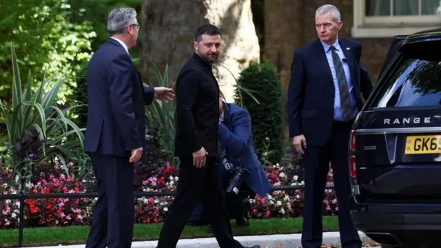 Zelensky departs Downing Street and Starmer walks behind him.