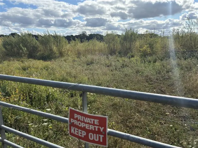 The site for the proposed stadium just a green land patch behind a gate