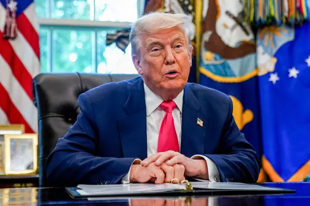 Trump speaking with an open folder in front of him from the Oval Office desk