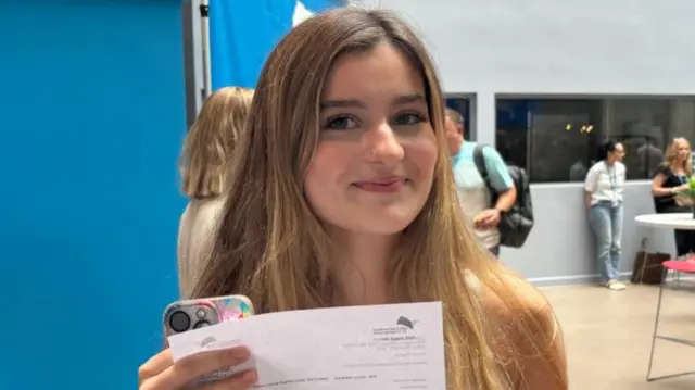 Meghan Cotty smiles and holds up her results paper