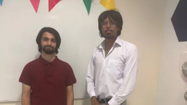 Shaheer Shafqat stands alongside another person holding results