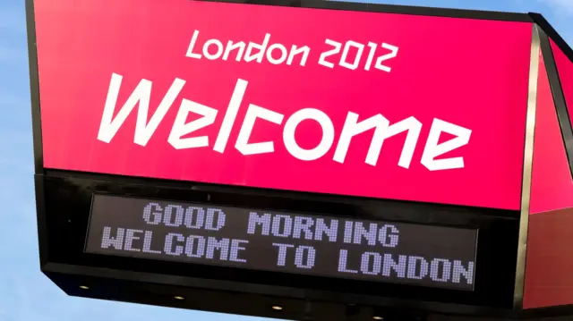 A sign which says: "London 2012 Welcome" and underneath a digital banner that reads "good morning welcome to London"