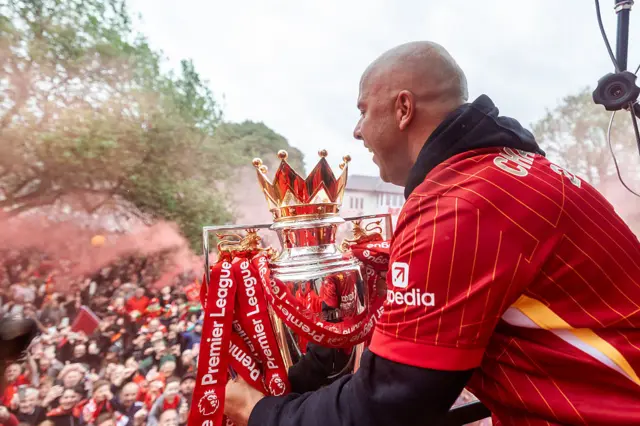 Arne Slot, head coach of Liverpool celebrates as the team bus passes through fans in celebration