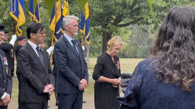 Left to right: Masaki Ikegami and Huw Irranca-Davies paying their respects in the rain