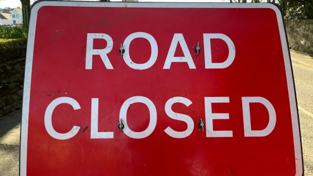 A red sign with white lettering that reads "Road Closed".