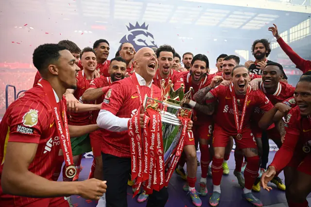 Arne Slot lifts the Premier League trophy surrounded by his squad
