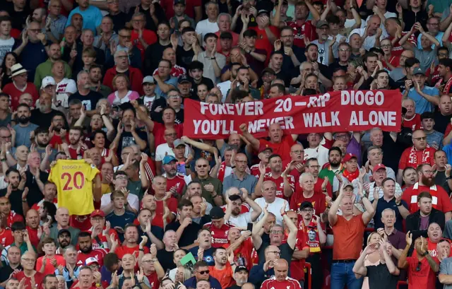 Fans hold up shirts and banners in tribute to Jota at full time as they chant his song