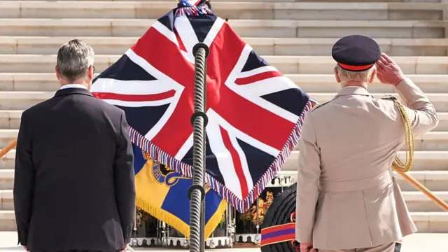 Keir Starmer and King Charles salute a British flag