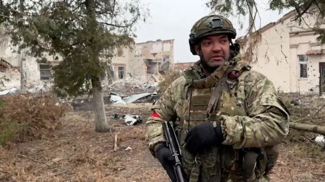A Russian army soldier walks along a ruined street of Malaya Loknya settlement
